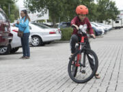 Judah Kadiasang, 9, a student at Crestline Elementary School, tries out his new bike Saturday in the parking lot of McCord&#039;s Vancouver Toyota while his mom, Helen Kadiasang, watches.