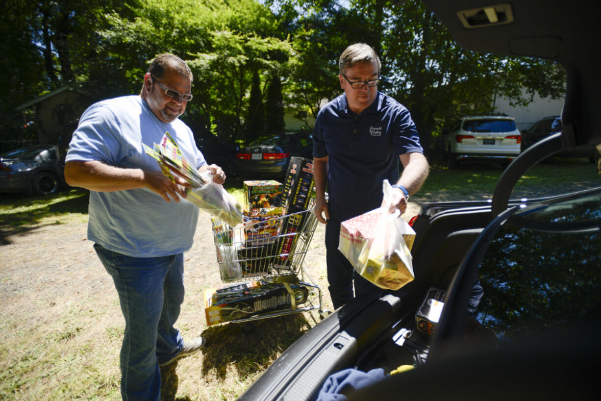 Tim Weiner, left, and Norm Peterson load fireworks from BlackJack Fireworks in Hazel Dell into their car Tuesday. Weiner says he has purchased fireworks every Fourth of July since 1982.