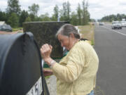 As traffic roars past, Lois Beard checks her mailbox on the shoulder of Highway 502.