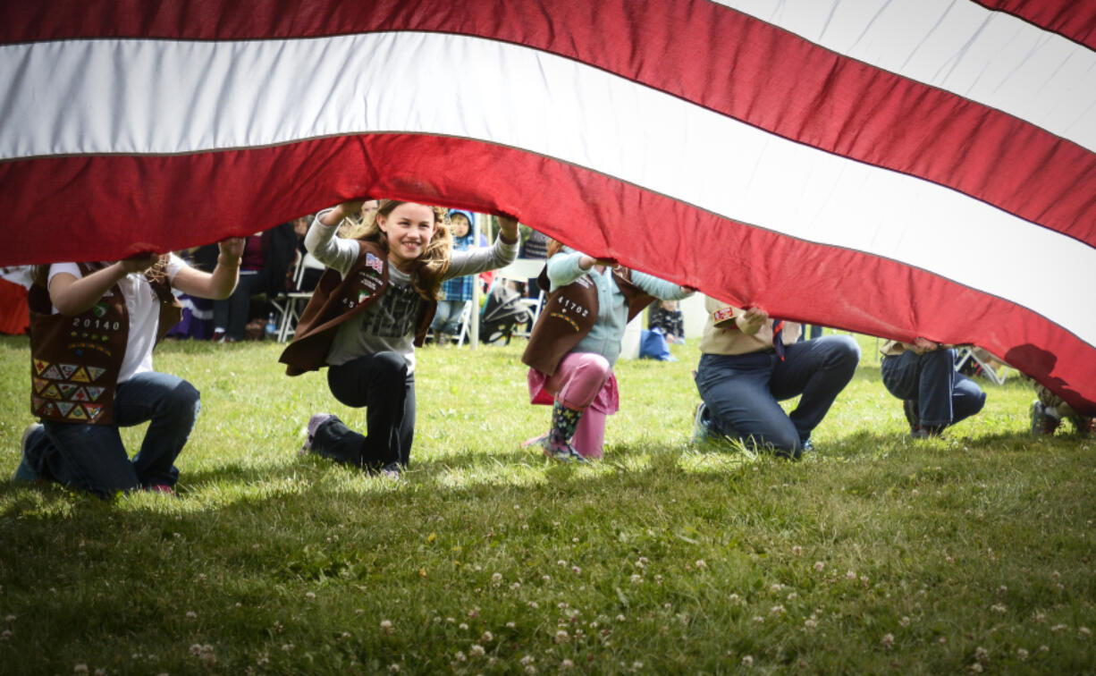 Mikaela Fisher, a member of Brownie Girl Scout Troop 45722, helps support a huge American flag during Fort Vancouver's Flag Day celebration in 2017.