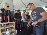 Gary Nylander of Vancouver, left, waits while Rick Nuttail pours him a glass of wine at the Rusty Grape Vineyard booth Sunday at the Craft Beer and WineFest of Vancouver in Esther Short Park.