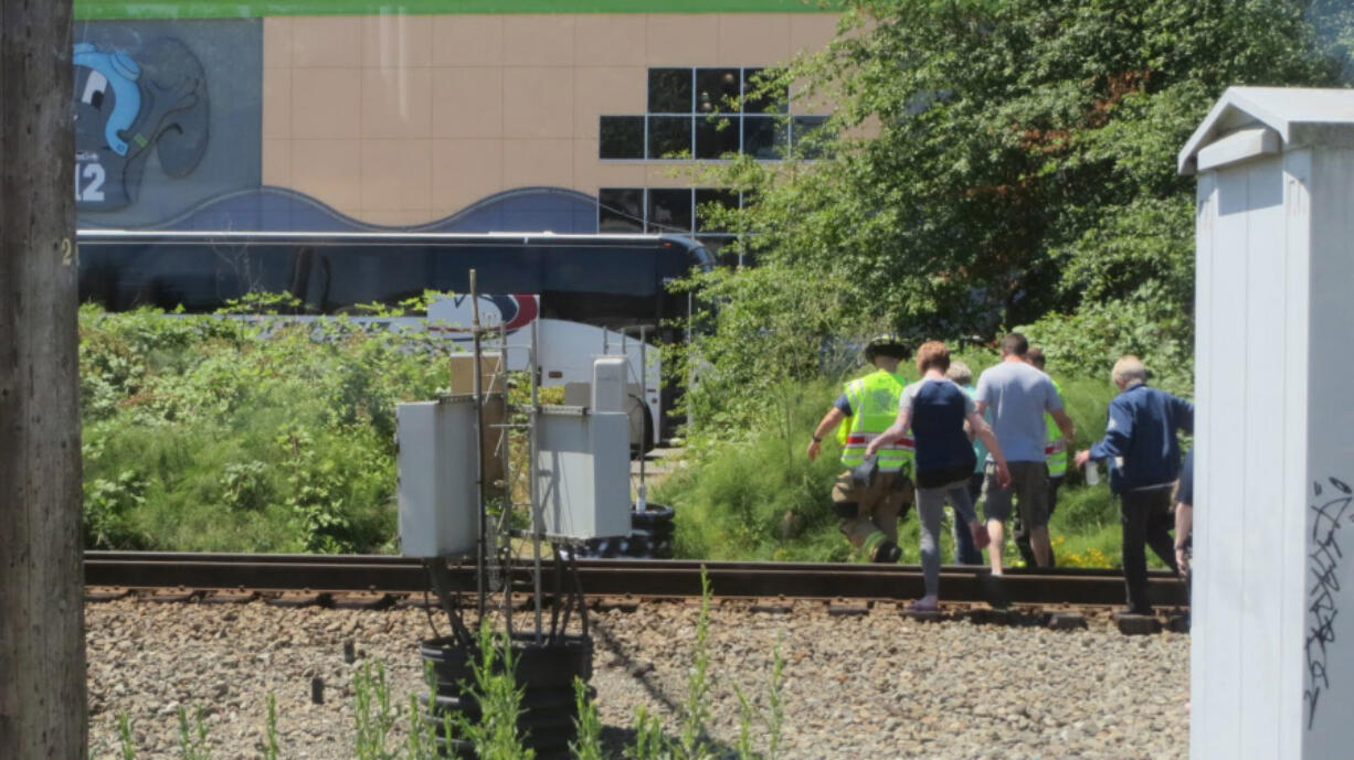 Passengers walk to buses parked nearby after their Amtrak train derailed Sunday afternoon south of Seattle.