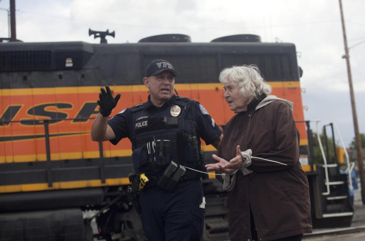 Imogene Williams, 85, is led away from downtown Vancouver railroad tracks in flex cuffs June 18. Unlike the 20 other protesters arrested, Williams&#039; hands were cuffed in front of her.