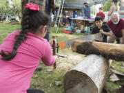 Valerie Rodriguez, 7, left, and brother Jonathan, 10, of Beaverton, Ore., cut a log with the help of Jeff Booth, a volunteer with the Pacific Crest Trail Association, Saturday at Fort Vancouver&#039;s National Get Outdoors Day festivities. Valerie and Jonathan came with their uncle Manny Rodriquez and his family, who live in Vancouver.