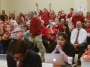 Oil terminal opponents in the audience waive their hands Monday in support of an opening statement critical of the proposed Vancouver Energy oil terminal during an Energy Facility Site Evaluation Council hearing Clark College at Columbia Tech Center.