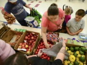 Nataliya Romashcheko, center, selects tomatoes with her son, Misha Romashcheko, 8, right, at the fresh food pantry at Orchards Elementary School on Wednesday.