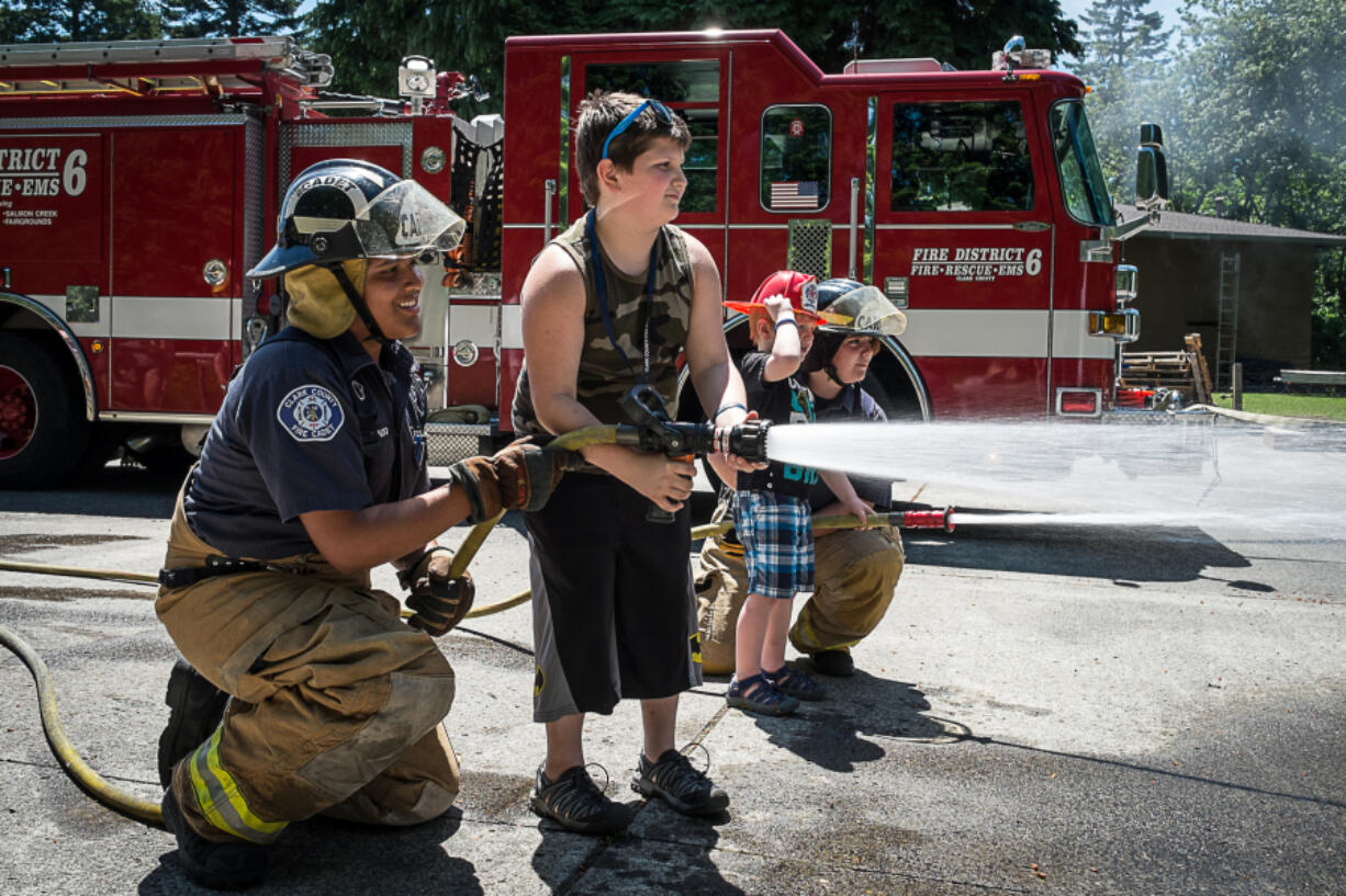 Chief Fire Cadet Roberto Villalplando helps 10-year-old Aydin McCulley use a fire hose. The junior firefighter challenge station at the Clark County Fire District 6 open house let kids try out the job for themselves.