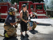 Chief Fire Cadet Roberto Villalplando helps 10-year-old Aydin McCulley use a fire hose. The junior firefighter challenge station at the Clark County Fire District 6 open house let kids try out the job for themselves.