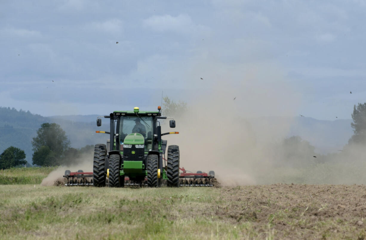 Tyler Behrendsen of Behrendsen Farms harrows the soil on a roughly 540-acre property on Lower River Road to prepare for grain planting. The Columbia Land Trust plans to shape the site into a sanctuary for migrating sandhill cranes. At top, in an October 2003 photo, a sandhill crane flies near the property on Lower River Road being managed as a sanctuary for the birds.