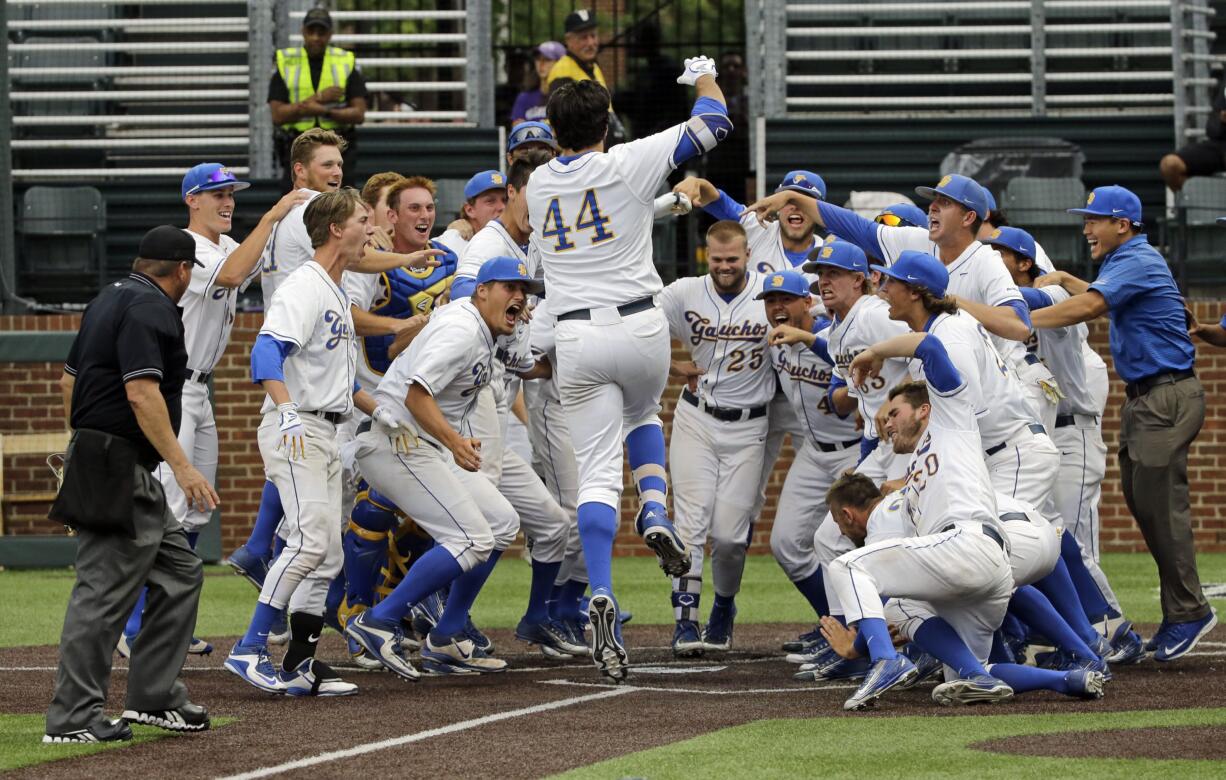 UC Santa Barbara's Austin Bush (44) crosses home plate as his teammates celebrate after Bush hit a walk-off home run against Washington in the 14th inning of an NCAA college baseball regional tournament game Friday, June 3, 2016, in Nashville, Tenn. The home run gave UC Santa Barbara a 3-2 win.