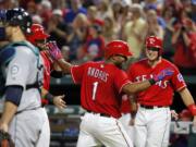 Seattle Mariners catcher Chris Iannetta, left, stands by the plate as Texas Rangers' Mitch Moreland, left rear, Elvis Andrus (1) and Ryan Rua, right rear, celebrate Andrus' three-run home run that scored the duo in the fifth inning of a baseball game, Saturday, June 4, 2016, in Arlington, Texas.