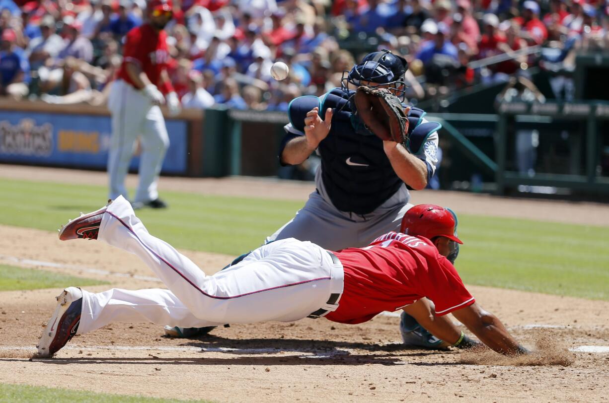 Texas Rangers' Elvis Andrus dives at home to score from third ahead of the throw to Seattle Mariners catcher Chris Iannetta in the fifth inning of a baseball game, Sunday, June 5, 2016, in Arlington, Texas. Andrus scored on a sacrifice fly by Bobby Wilson.