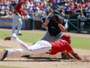 Texas Rangers' Elvis Andrus dives at home to score from third ahead of the throw to Seattle Mariners catcher Chris Iannetta in the fifth inning of a baseball game, Sunday, June 5, 2016, in Arlington, Texas. Andrus scored on a sacrifice fly by Bobby Wilson.