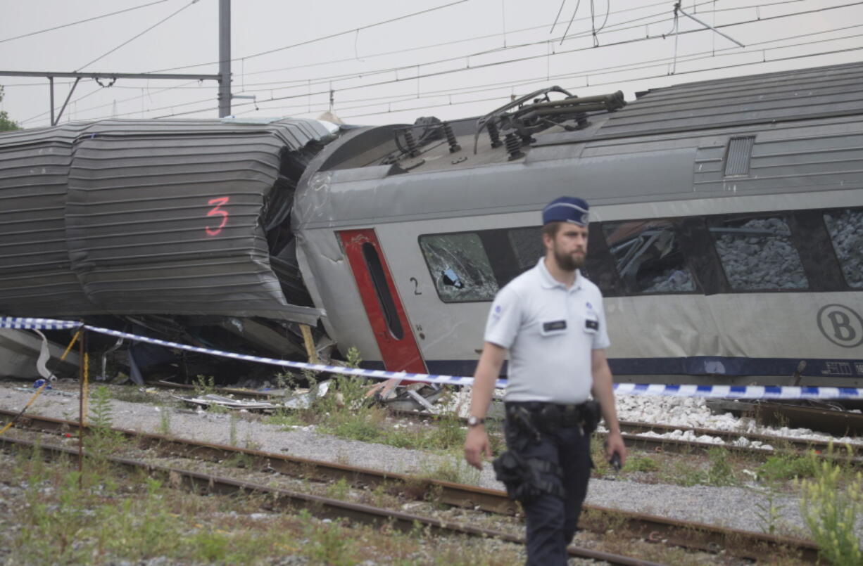 A police officer walks by the wreckage of a passenger and freight train Monday after they collided in Hermalle-sous-Huy, Belgium.