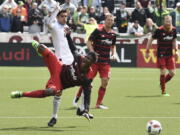 Portland Timbers forward Dairon Asprilla (11) is tripped by Vancouver Whitecaps midfielder Matias Laba, back left, during the second half of an MLS soccer game in Portland, Ore., on Sunday, May 22, 2016.