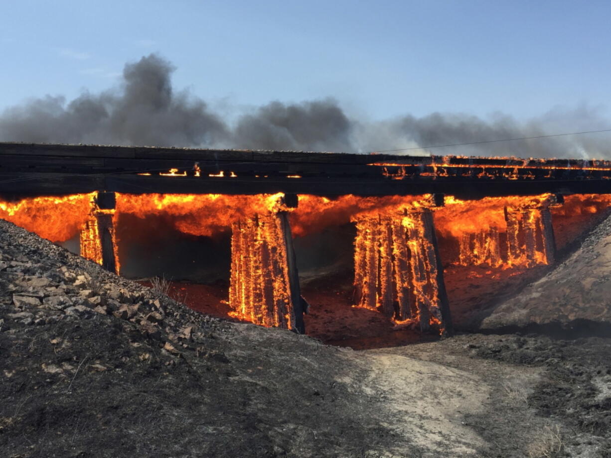 A railroad trestle burns Wednesday near the tiny town of Haswell, Colo. For days, wildfires have raged amid spiking heat across Southern California and much of the West, forcing many to evacuate.