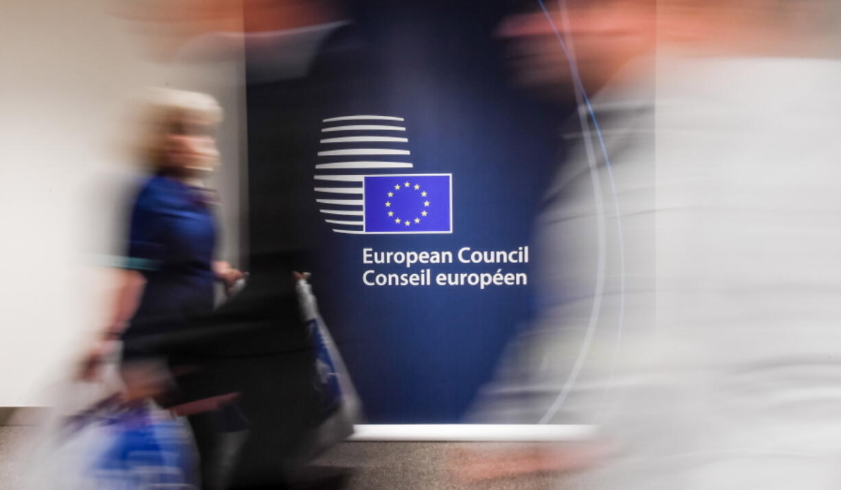 People walk by a sign in English and French in the press room at an EU summit in Brussels on Tuesday, June 28, 2016. Of all the myriad challenges facing the European Union with the pending departure of Britain, one unlikely issue to be resolved is the fact that English would no longer be an official language.