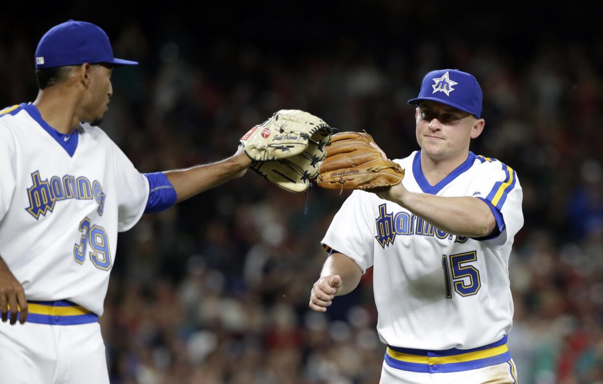 Seattle Mariners relief pitcher Edwin Diaz, left, reaches out to congratulate third baseman Kyle Seager on a play in the eighth inning of a baseball game against the St. Louis Cardinals Saturday, June 25, 2016, in Seattle.