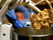 Cookie dough clings to the beaters of a standing mixer.