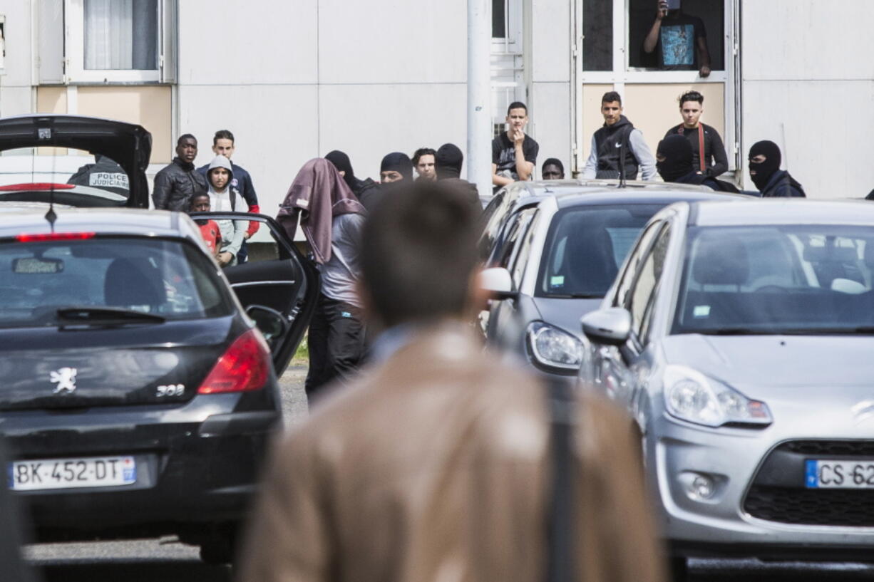 Police detain a suspect, his face covered by a piece of clothing, during a raid linked to the killing of two police officers Tuesday in Mantes-la-Jolie, a suburb of Paris.