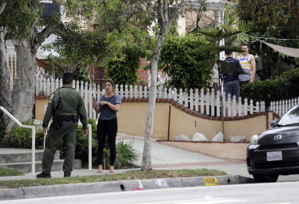 A Santa Monica community service officer and onlookers stand across the street from where investigators are viewing a car after a heavily armed man was arrested in Santa Monica, Calif., early Sunday. The man reportedly told police he was in the area for West Hollywood&#039;s huge gay pride parade. Authorities did not know of any connection between the gay nightclub shooting in Orlando, Fla., early Sunday and the Santa Monica arrest.