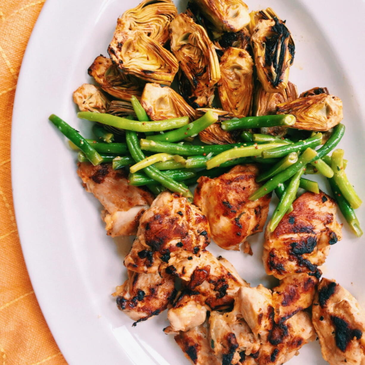 Grilled chicken and artichokes flavored with a lemony marinade (AP Photo/Katie Workman)