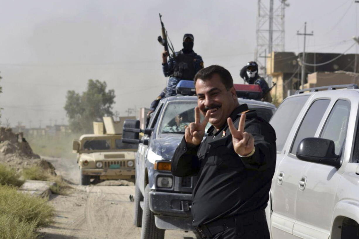 A member of the Iraqi security forces flashes a victory sign as they celebrate Friday in central Fallujah, Iraq, after retaking the city from Islamic State militants.