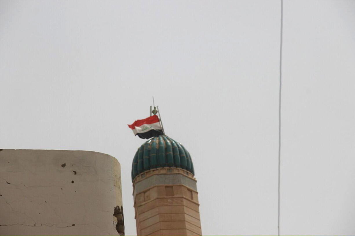 The Iraqi national flag flies Sunday atop a minaret in Fallujah, Iraq, after Iraqi forces re-took the city center, which has been controlled by Islamic State for two years.