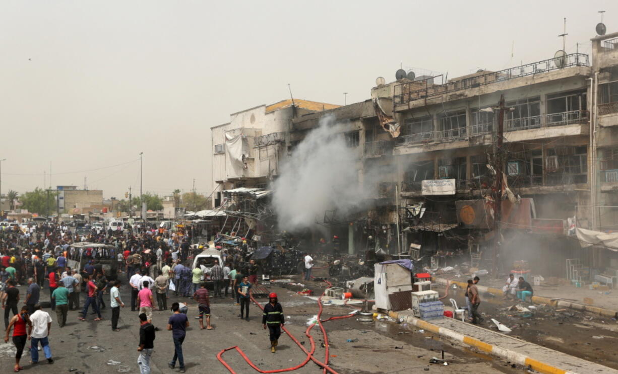 Smoke rises as Iraqi security forces and civilians gather at the scene of a deadly suicide car bomb attack in the neighborhood of New Baghdad, Iraq, Thursday. Two separate suicide attacks in and outside the Iraqi capital have killed at least 27 people and wounded dozens. Officials say the deadliest bombing took place in New Baghdad, a commercial area of a majority Shiite neighborhood in Baghdad, killing over a dozen civilians. Another suicide bomber rammed his explosives-laden car into an Iraqi army checkpoint north of Baghdad, killing at least 12 people.