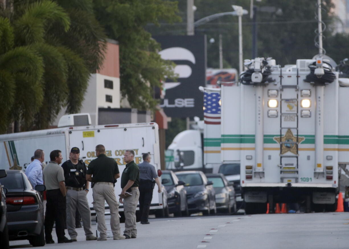 Law enforcement officials confer near the Pulse Orlando nightclub before sunrise Monday in Orlando, Fla. Pulse Orlando was the scene of a mass fatal shooting early Sunday morning.