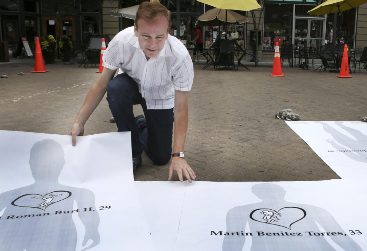 Walt Boyle, a local branding strategist, puts together a temporary memorial for the victims of the Orlando massacre in Market Square downtown Roanoke, Va., on Wednesday. It features 49 life-size silhouettes and short bios for each person killed.