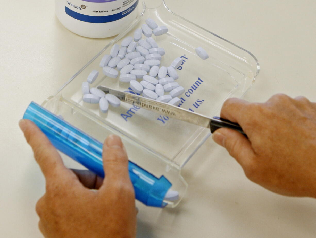 A pharmacy tech poses for a picture with prescription medication at a pharmacy in Edmond, Okla. More than a dozen websites and apps are vying to help U.S. consumers find the lowest prices for prescription drugs by comparing prices and searching for deals, similar to the way Expedia looks for cheap airfare or Bankrate.com looks for low mortgage rates.