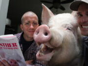 In this undated photo Esther The Wonder Pig is shown with her owners Derek Walter, left, and Steve Jenkins in Campbellville, Ontario. Walter is holding a book titled &quot;Esther The Wonder Pig: Changing the World One Heart at a Time,&quot; which the two wrote about their pet pig.