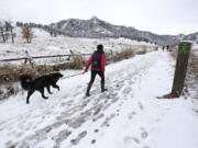 A woman walks her dog into local open space wildland at Chautauqua Park, in Boulder, Colo.