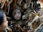 A village girl, in a cape mostly of dried banana leaves and covered in mud, attends Mass in an annual ritual to venerate her village&#039;s patron saint, John the Baptist, Friday, June 24, 2016 at Bibiclat, Aliaga township, Nueva Ecija province in northern Philippines. The &quot;Taong Putik&quot; or &quot;mud people&quot; festival in Bibiclat village dates back to the Japanese occupation of the Philippines in the 1940s.