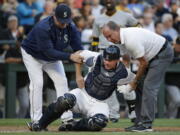 Seattle Mariners catcher Steve Clevenger, center, is helped to his feet by manager Scott Servais, left, and trainer Rick Griffin after Clevenger was injured during the third inning of a baseball game against the Pittsburgh Pirates on Wednesday, June 29, 2016, in Seattle. Clevenger left the game.