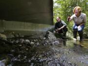 FILE - In this June 22, 2015, file photo, Julie Henning, right, division manager of the Washington Dept. of Fish and Wildlife ecosystem services division habitat program, and Melissa Erkel, left, a fish passage biologist, look at a wide passageway for the north fork of Newaukum Creek near Enumclaw, Wash. Federal appeals judges say the state of Washington has violated the treaty rights of tribes to fish by building and maintaining large pipes that allow streams to pass beneath roads but also block migrating salmon. (AP Photo/Ted S.