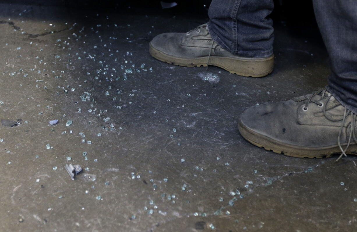 Broken glass from a car window litters the ground as Jeremiah Munavu, lead technician at Auto Glass Now in San Francisco, installs a new window.