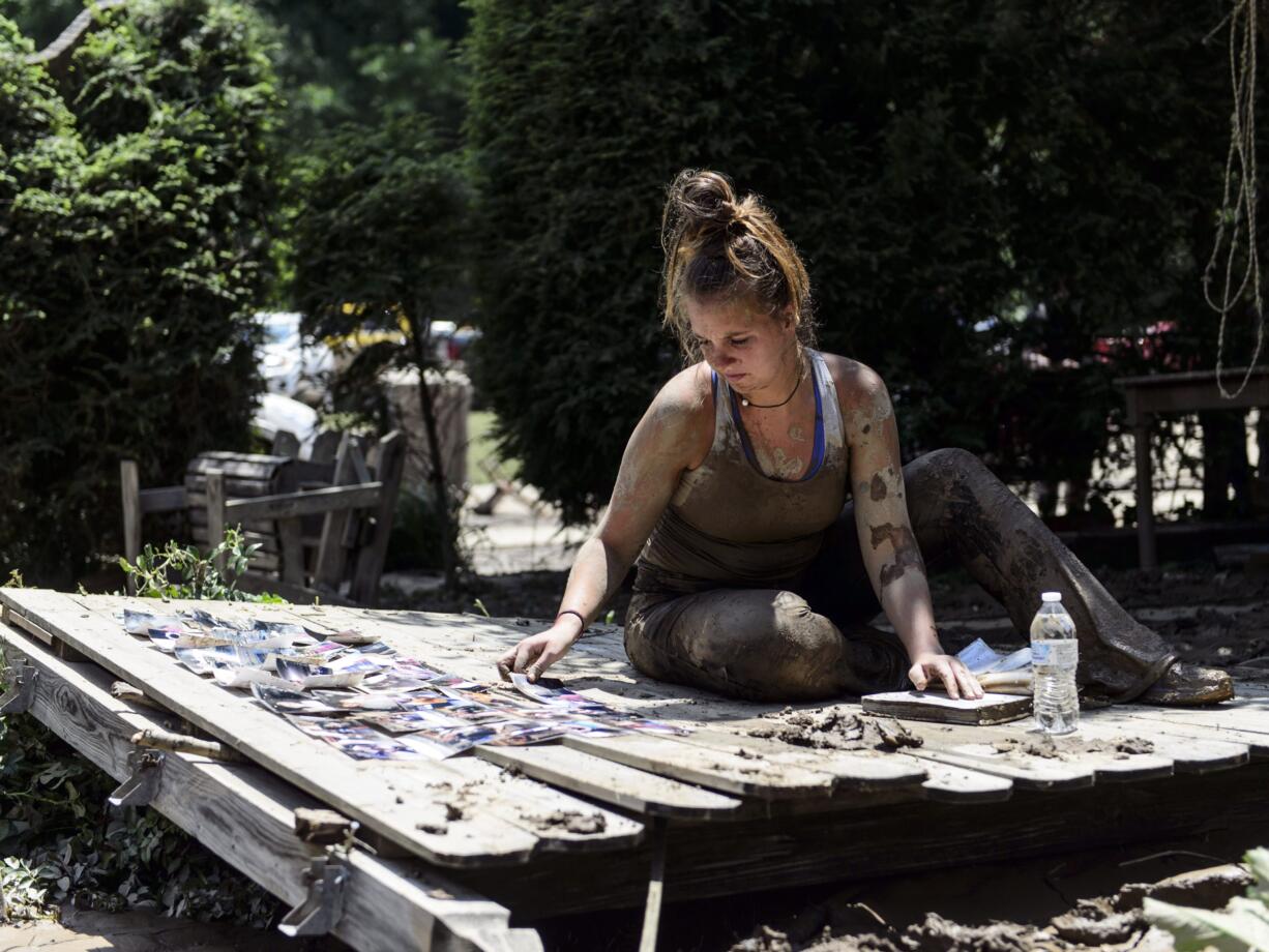 Taylor Self of Charleston lays pictures out to dry as she takes a break from cleaning Sherry and Kelly Cole's house, who are her best friend's parents, in Clendenin, W.Va., on Saturday, June 25, 2016. Self drove from Charleston early Saturday morning once she saw pictures of the damage done by flooding on Sherry Cole's Facebook page.  The scene in Clendenin, located in Kanawha County, wasn't as deadly as in Ranielle. Sixteen people died in Greenbrier County, at least 15 of them in Ranielle. Greenbrier is the only county where Gov. Earl Ray Tomblin's administration believes people remain missing.