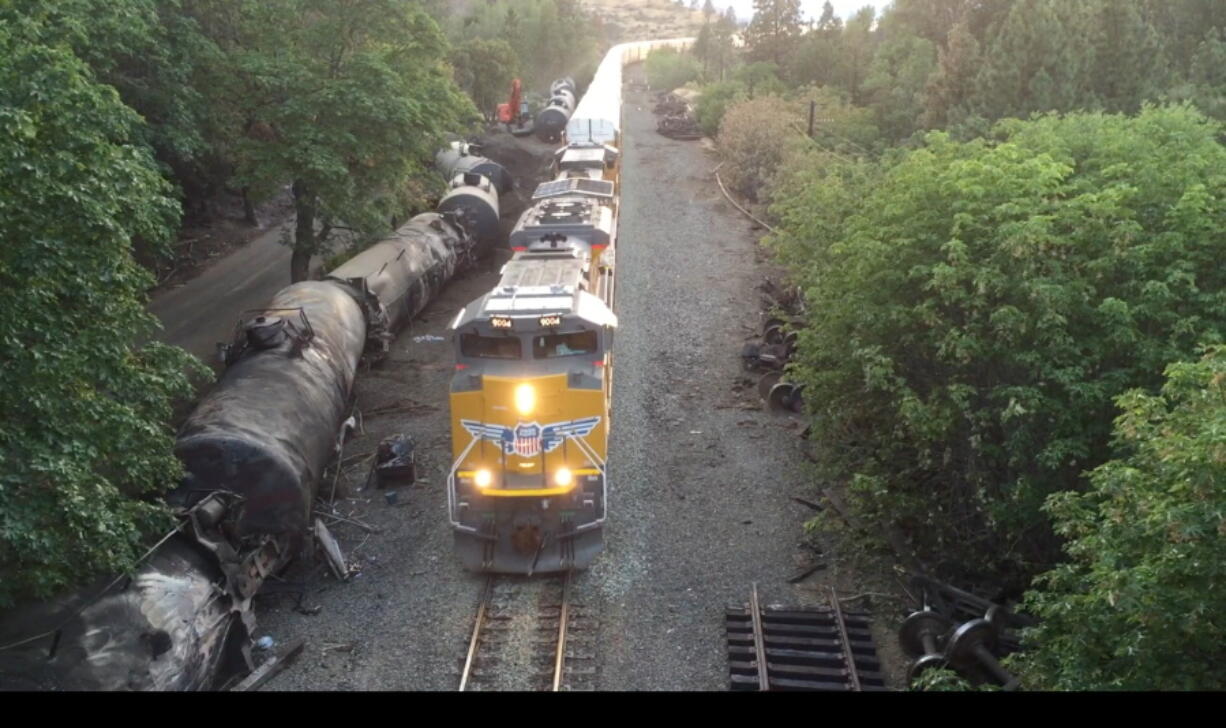 Crumpled oil tankers lie beside the railroad tracks after a fiery train derailment on June 3 that prompted evacuations from the tiny Columbia River Gorge town about 70 miles east of Portland in Mosier, Ore. Trains began running Sunday and at least eight had moved through the town of about 400 people carrying mixed goods --. Union Pacific defended its actions Monday, saying it was safe to run other trains by while crews continued to drain oil from the crashed tankers.