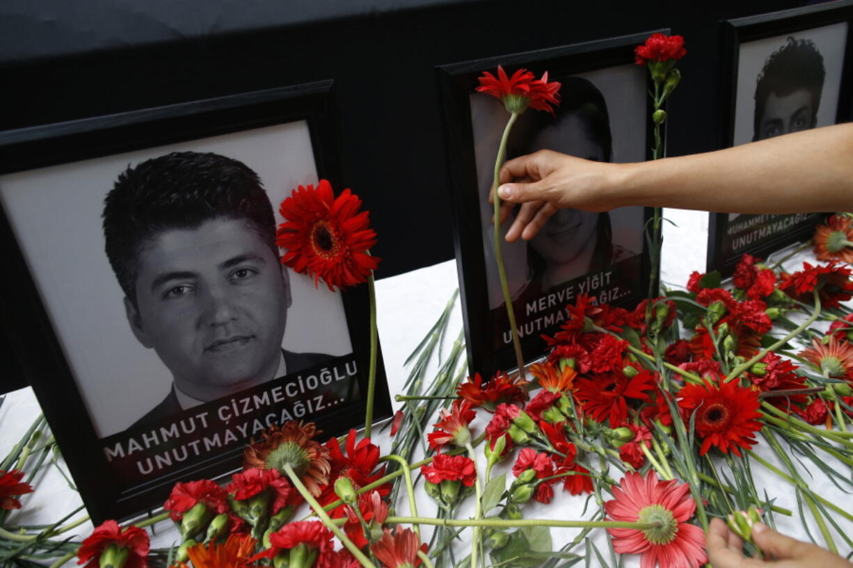 Photographs of victims displayed among carnations as family members, colleagues and friends gather for a memorial ceremony at the Ataturk Airport in Istanbul, Thursday.(AP Photo/Emrah Gurel)