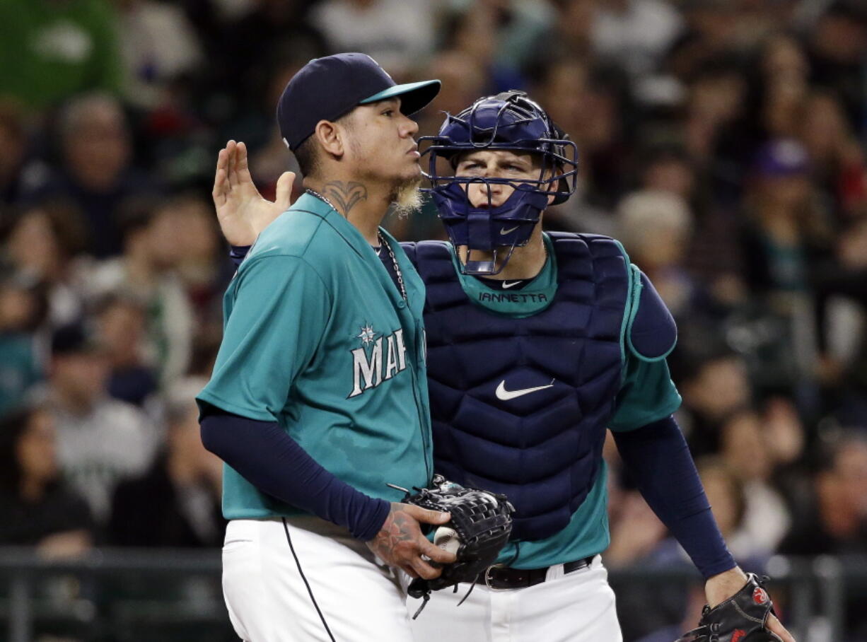 Seattle Mariners catcher Chris Iannetta, right, gives a pat to starting pitcher Felix Hernandez after a play during the third inning of a baseball game against the Minnesota Twins on Friday, May 27, 2016, in Seattle. Hernandez gave up five runs in the inning.