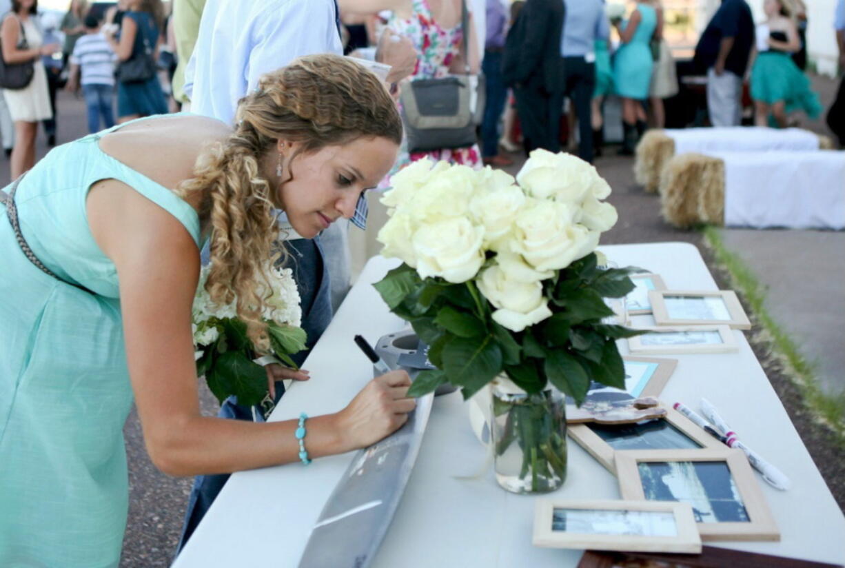 A bridesmaid writes a note on a propeller used as a wedding guest &quot;book&quot; by a couple who are pilots at Winslow-Lindbergh Airport in Winslow, Ariz.