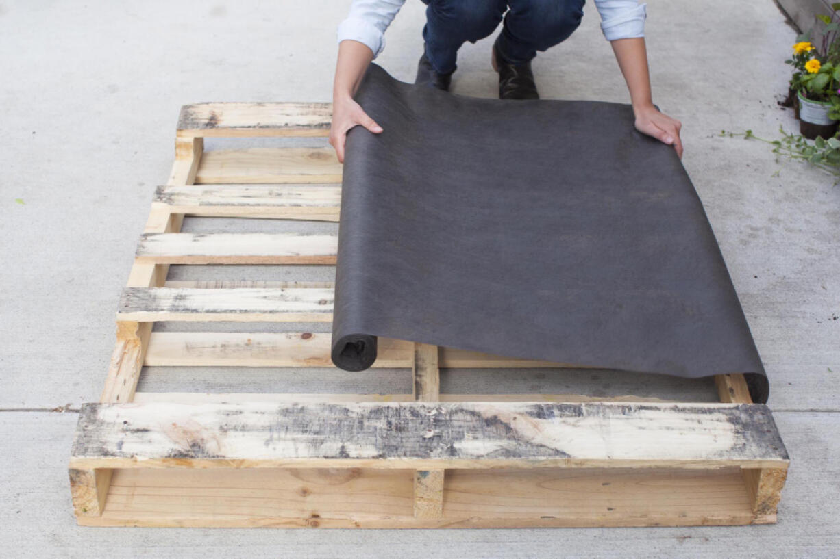 Lay your pallet flat, with the side you want facing front on the ground; it should have several horizontal planks. Cut landscaping fabric to cover the back and sides of the pallet.