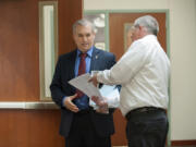 Clark County Councilor David Madore, left, is served with a summons by process server Brian Davis Tuesday morning at the Clark County Public Service Center.