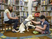 Cora McGill, 9, reads &quot;The Time of the Fireflies&quot; to Limon and Cindy Bean, left, the therapy dog&#039;s handler, on July 21 at the Ridgefield Community Library.