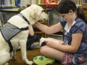 Cora McGill, 9, reads the &quot;The Time of the Fireflies&quot; to Limon as part of the Ridgefield Community Library&#039;s Read to Dogs program.