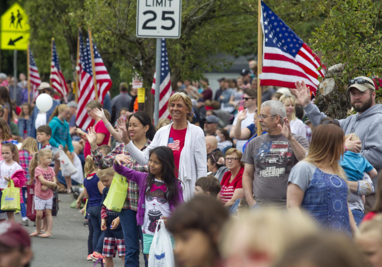 Spectators wave at passing floats at the Fourth of July Parade through the town of Ridgefield Monday.