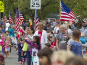 Spectators wave at passing floats at the Fourth of July Parade through the town of Ridgefield Monday.