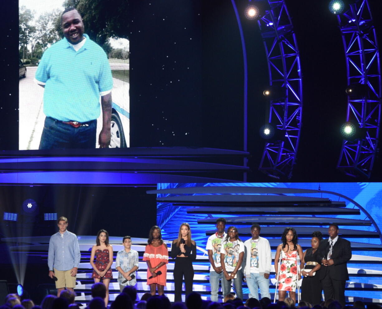 Jessica Alba, with families of victims of gun violence, speaks Sunday while a picture of Alton Sterling appears onscreen at the Teen Choice Awards in Inglewood, Calif.